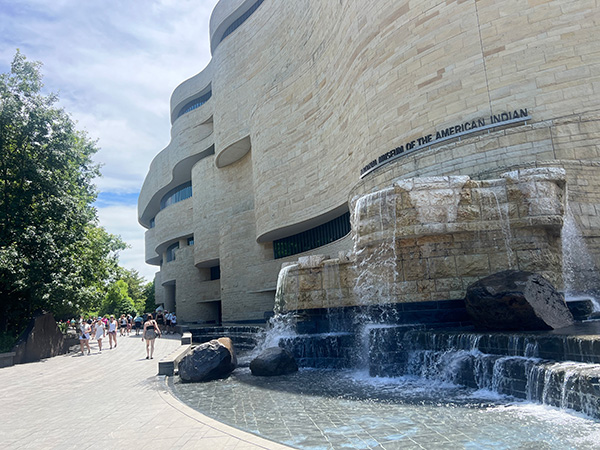 Exterior waterfall at the National Museum of the American Indian. Visitors walk along a nearby outdoor path.