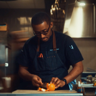 Chef Anthony Jones preparing citrus in a restaurant kitchen while working at a countertop.