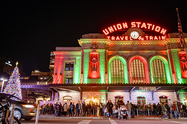 Denver Union Station lit up red and green with holiday tree