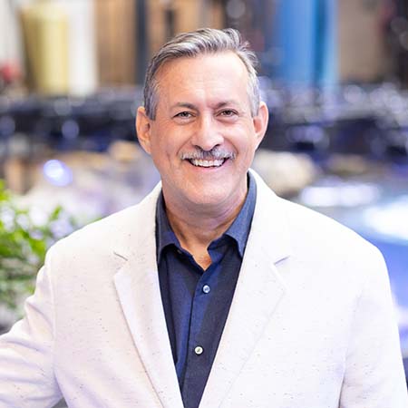 Portrait of Dr. Paul Anderson smiling in front of an aquarium exhibit.
