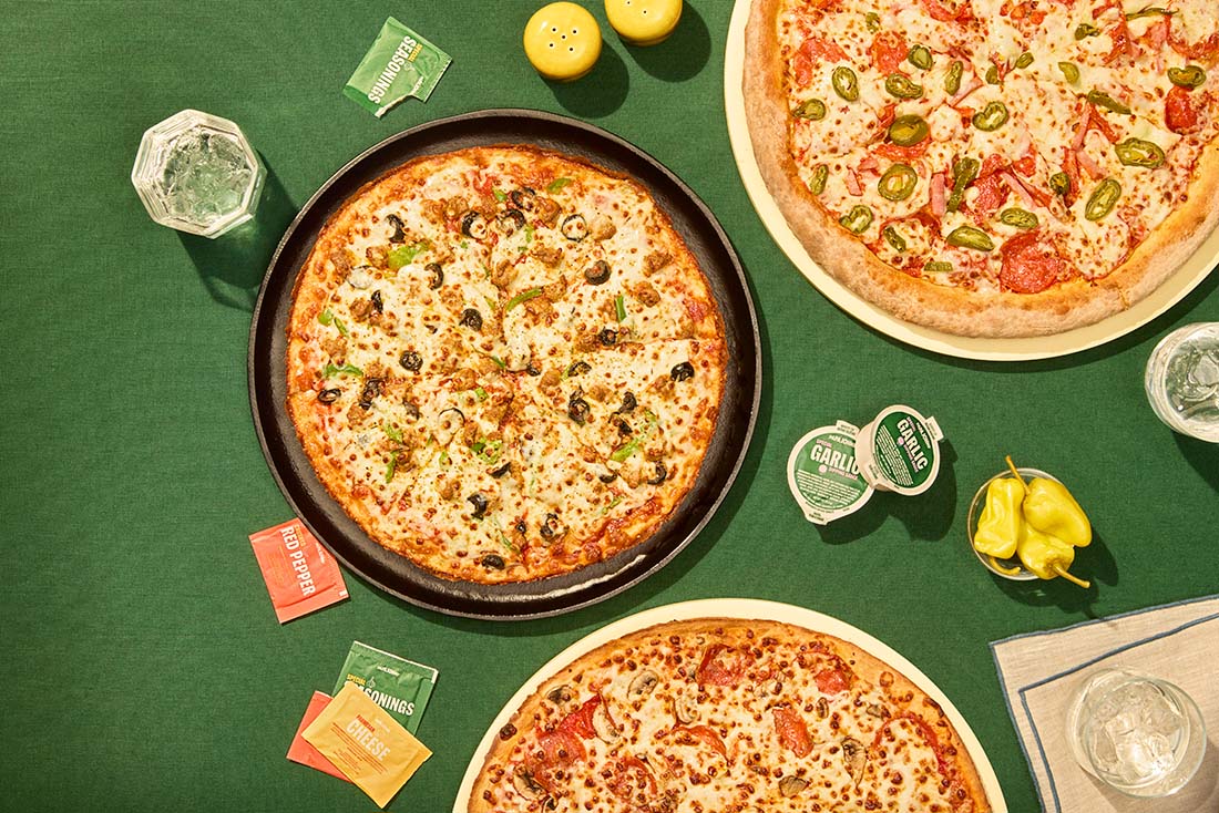 Two pizzas and dipping sauces arranged on a table.