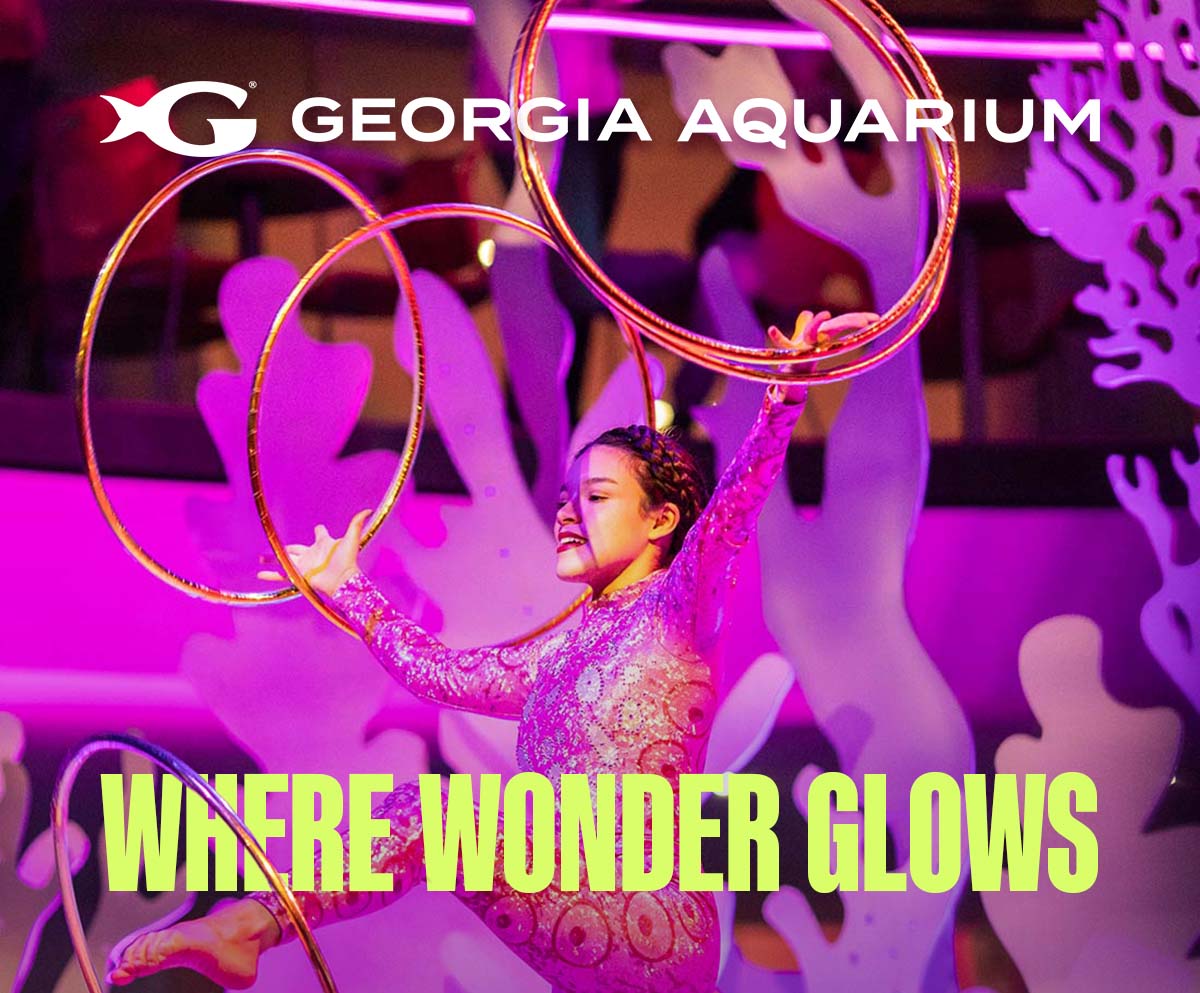 Performer in colorful costume with hula hoops under purple and pink lights at Georgia Aquarium's Glow Nights event, with "Where Wonder Glows" text overlay