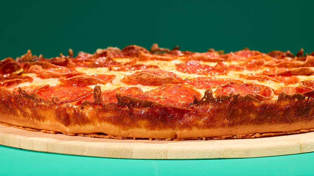 A Papa John's pizza on a teal plate  