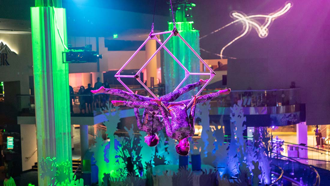 Aerial and cirque-style performers under neon lights at Glow Nights