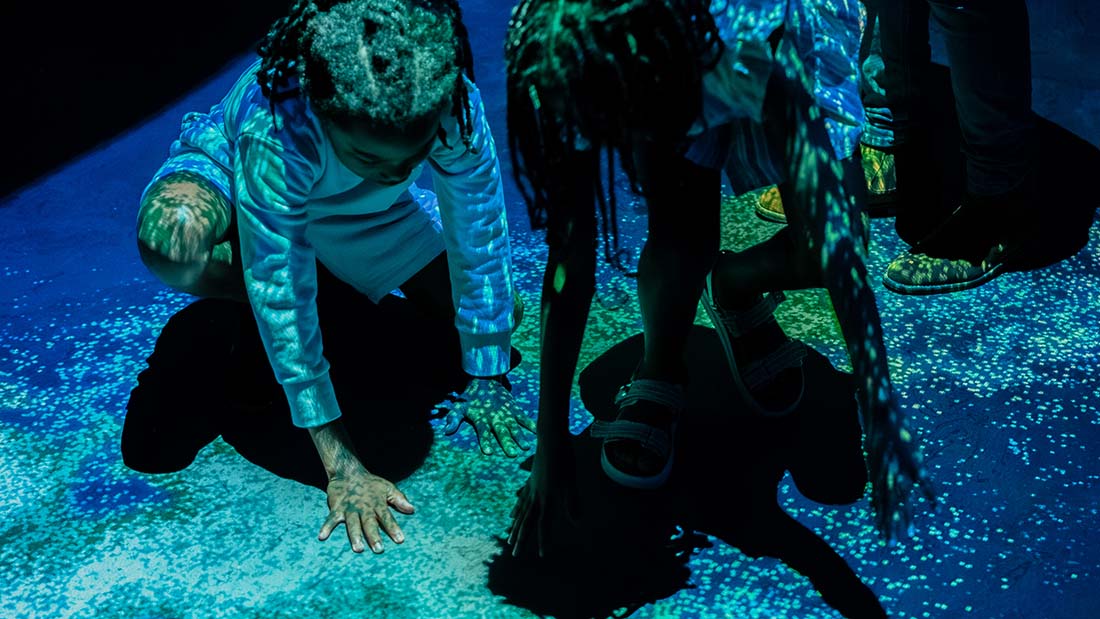 Kids playing in Georgia Aquarium's bioluminescence exhibit, Ocean Lights