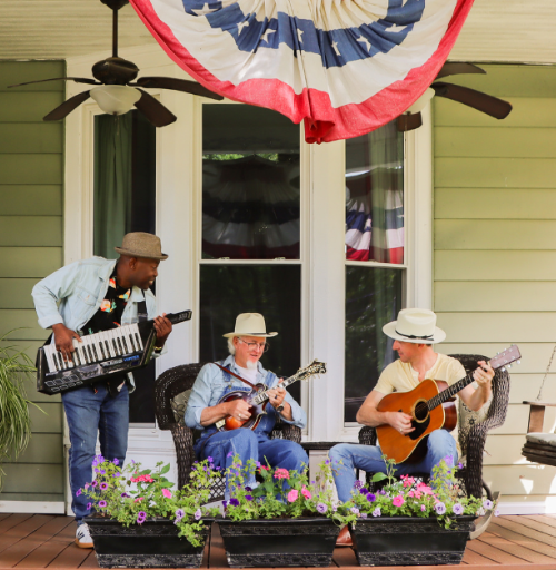 Three local musicians playing keys, guitar, and mandolin on a historic front porch in Henderson, Kentucky.