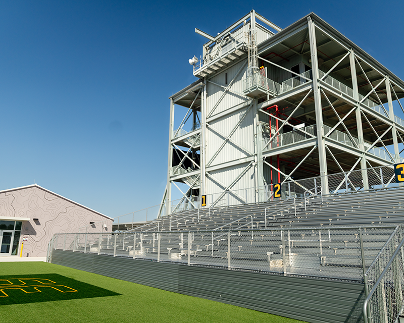 a stadium with a large building and a green field