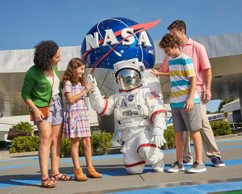 a group of people standing around a person in a space suit