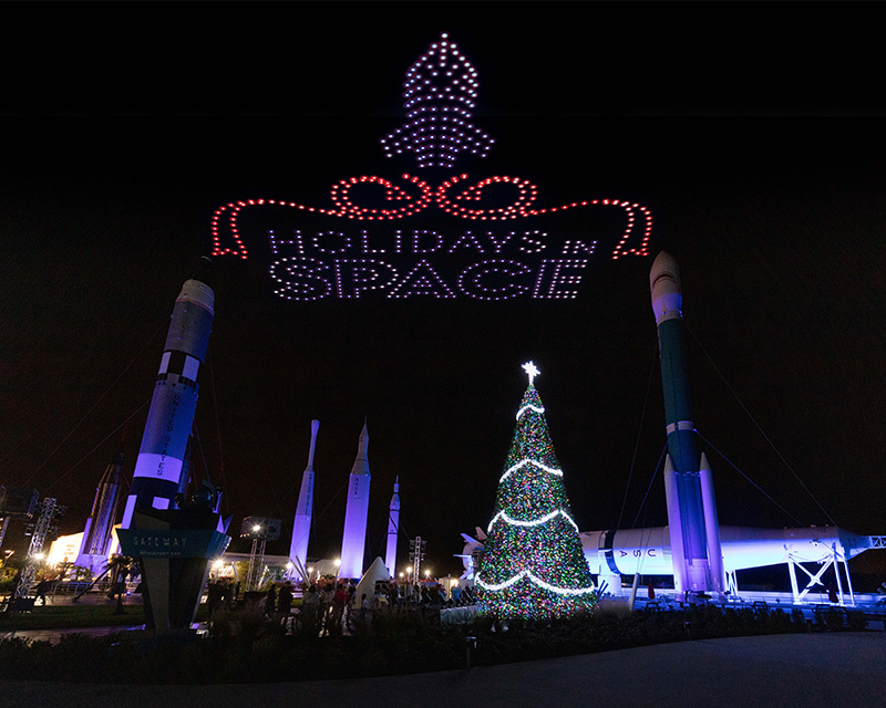 a christmas tree and rocket shaped lights over a rocket launch