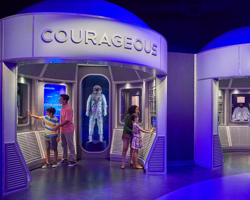 a group of people standing in a room with a display