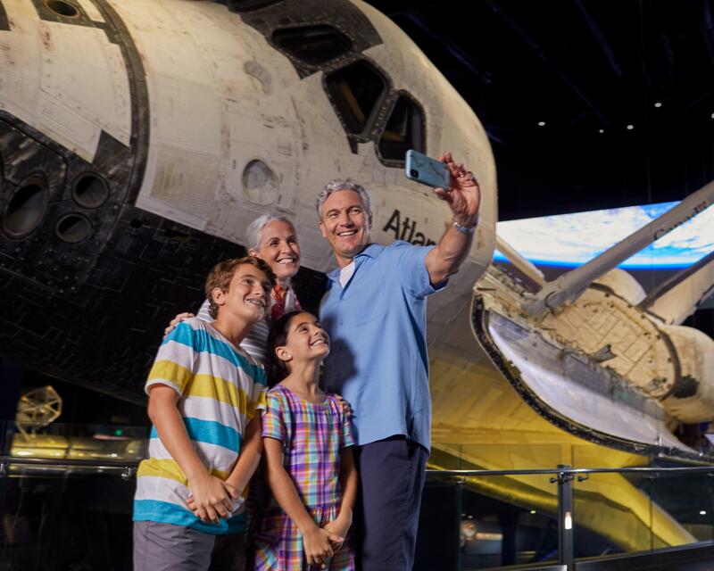 a group of people taking a selfie in front of a space shuttle