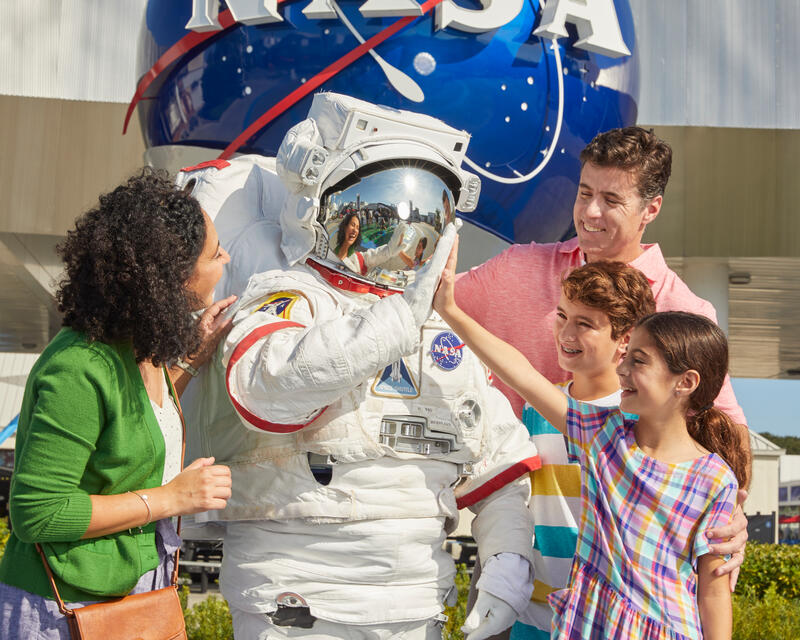 a group of people standing around a person in a space suit