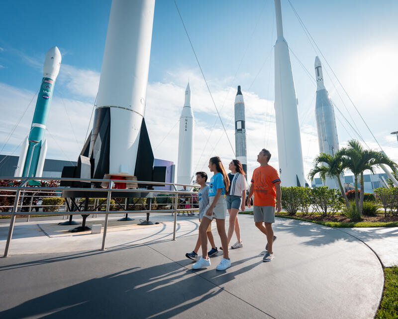 a group of people walking in front of a rocket display
