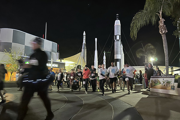 a group of people running in front of a rocket display