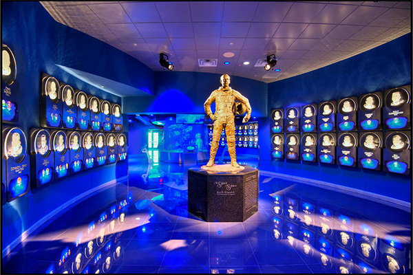 a statue of a man in a blue room with many framed pictures