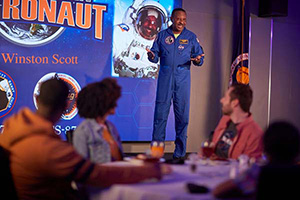 a man in a space suit speaking to a group of people