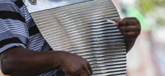 Close-up shot of a man's hands strumming the washboard.