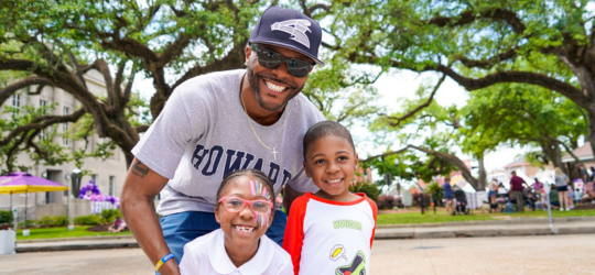 A man and two children smile at a community event in Houma.