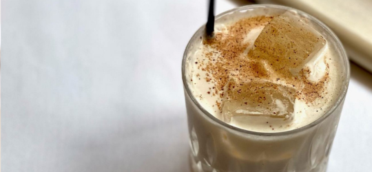 A close-up image of a glass of Brandy Milk Punch. 