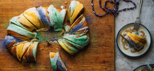 King Cake sliced atop a cutting board. 