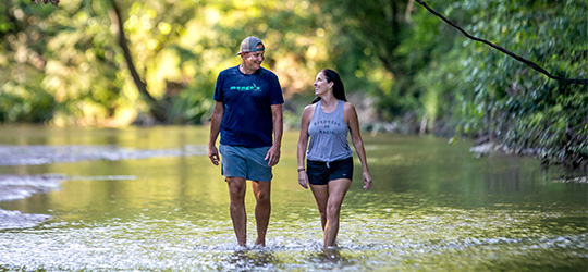 Two people walk through a creek at Tunica Hill Wildlife Management Center.