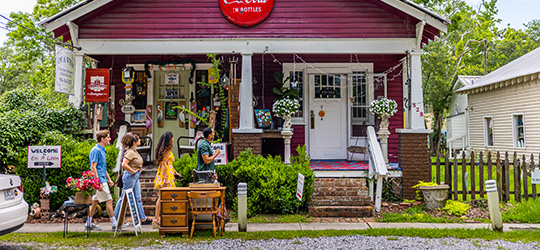 A group of people walk down a street, where they pass an antique store. 