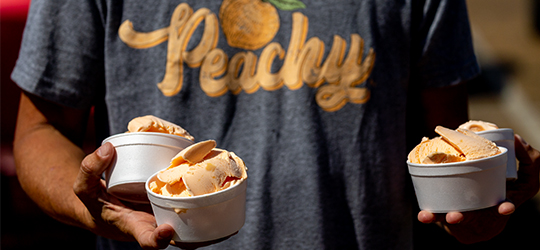 A person carries bowls of peach ice cream.