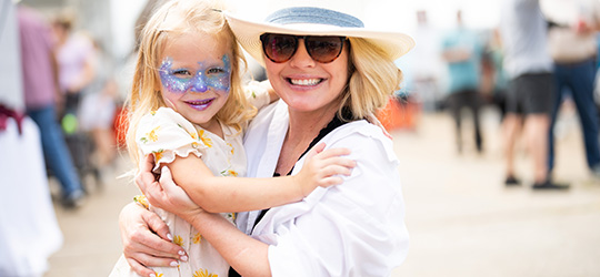 A person holds their child, who is wearing blue face paint.