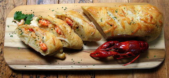 Sliced crawfish bread rests on a cutting board.