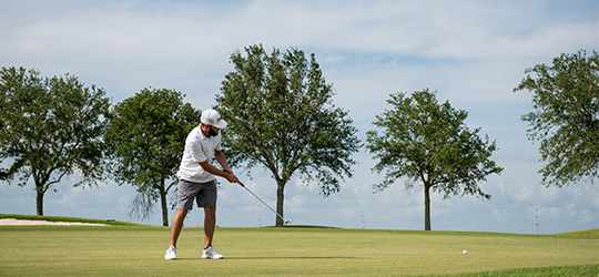 A golfer swings on the green.