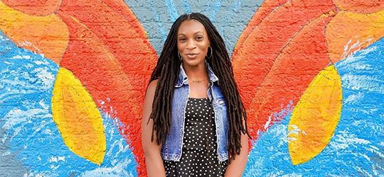 A traveler poses against a vibrant mural in downtown Houma.