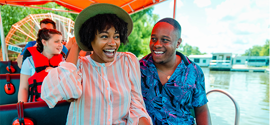 A couple laughs as they ride a tour-boat through a swamp.