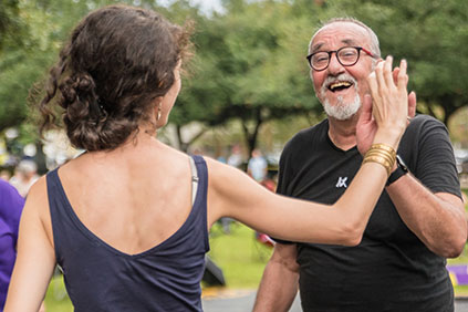Two people smile and high-five each other at an outdoor gathering.
