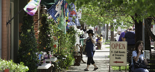 A woman walks along a charming downtown street, with flags stretching from building exteriors.