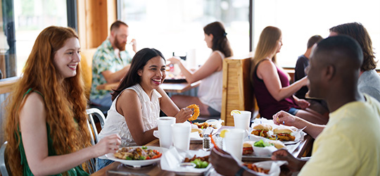 A group of people laugh around a table filled with Louisiana delicacies.