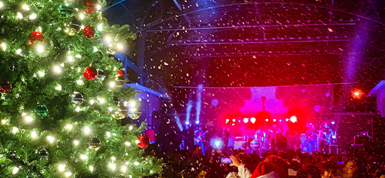 A Christmas festival in Lafayette, featuring snow, Christmas trees and a brightly lit stage.
