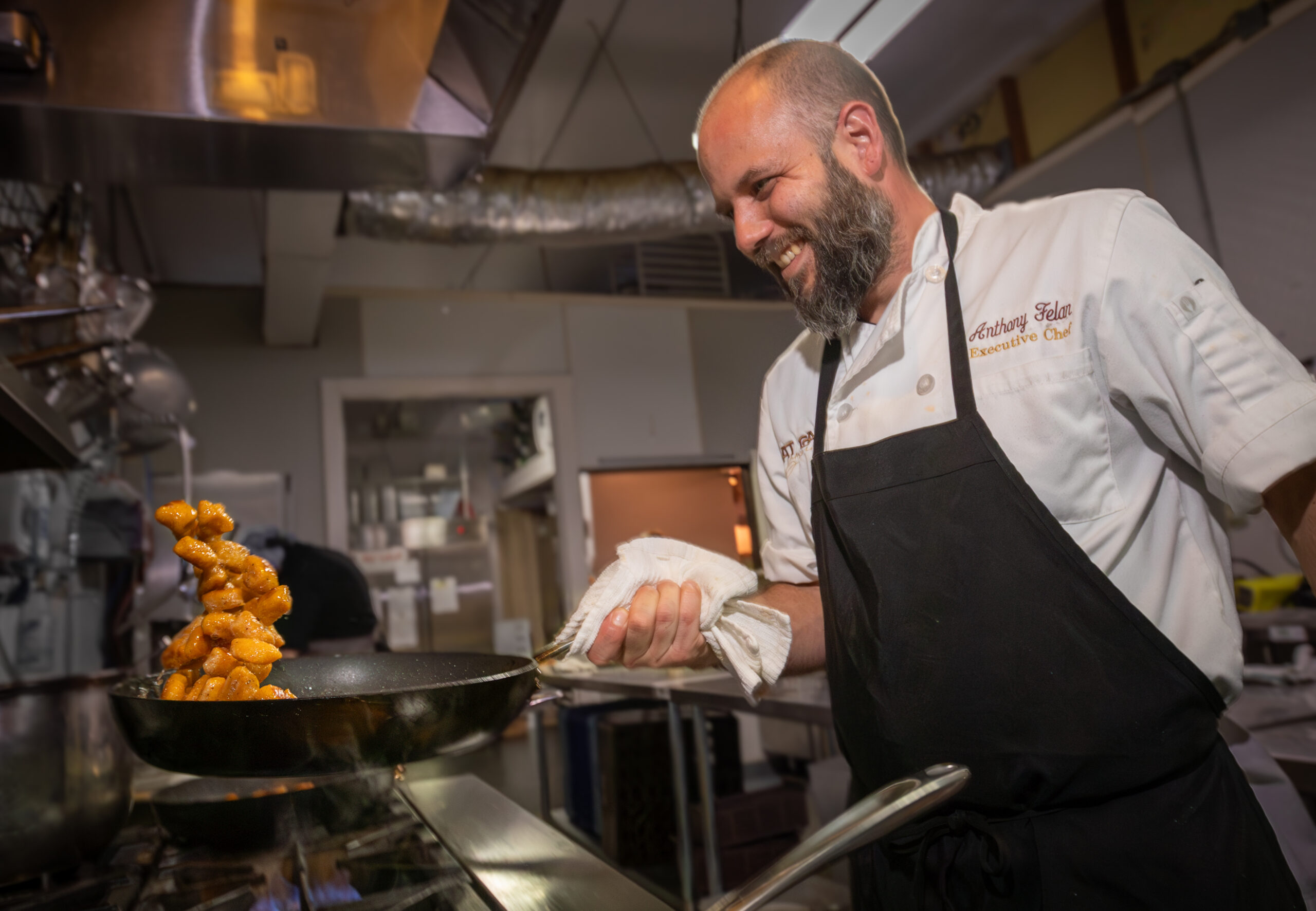 A chef tosses a dish in a skillet.