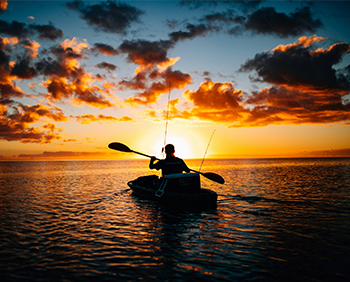 A person kayaks at sunset.