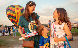 A family laughs together, enjoying the colorful balloons around.