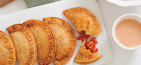 Crawfish hand pies, served with a creamy red sauce.