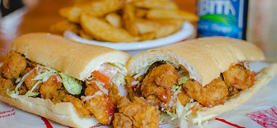 A fried shrimp po'boy, fries and an Abita beer.