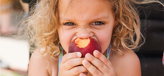 A child bites into a Louisiana peach.