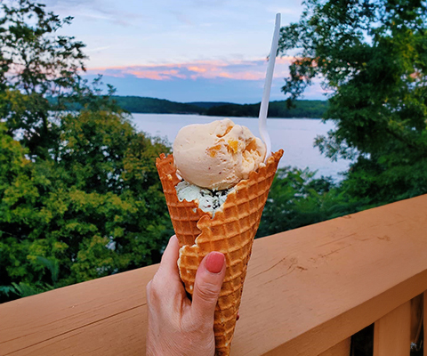 A picture of a woman's hand displaying a very tasty waffle cone filled with ice cream.