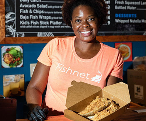 A picture of a woman displaying fried catfish from the Fishnet Restaurant.