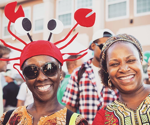 Picture of two smiling women, one wearing a crab hat.