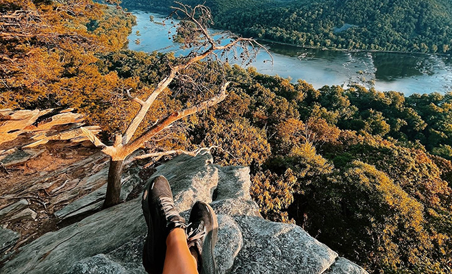 Picture of a beautiful view of Fall foliage from top of a mountain rock.