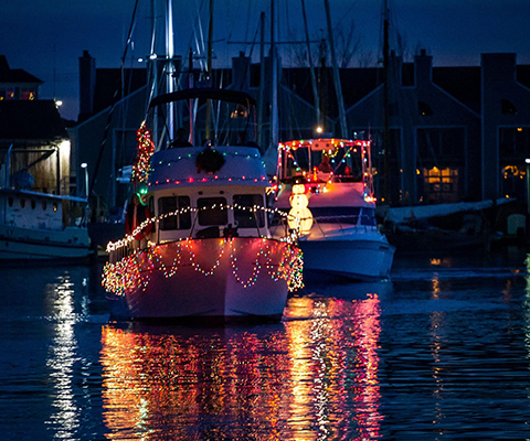 A picture of boats decorated and participating in a Holiday Boat Parade.