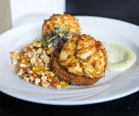 Crab cakes with fried green tomato and corn.