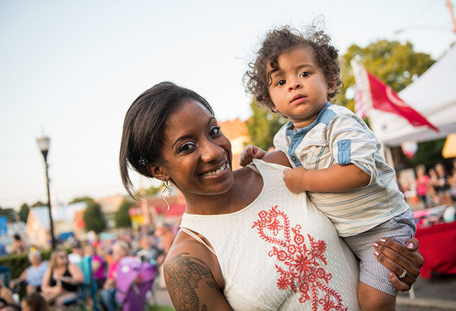 Mom carrying her son and enjoying a festival together.