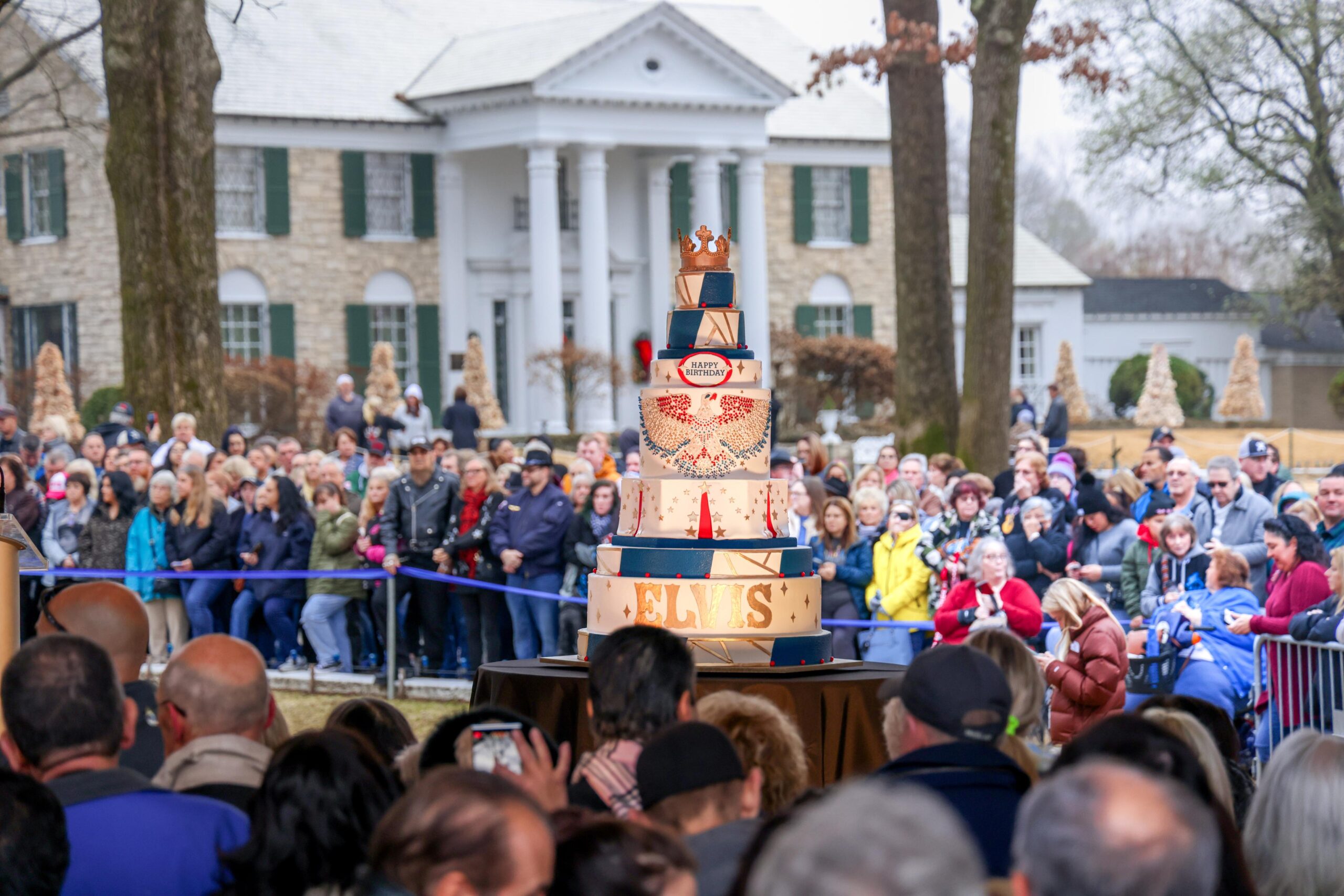 Crowds gathering around a tiered birthday cake at Elvis' Birthday Celebration at Graceland.